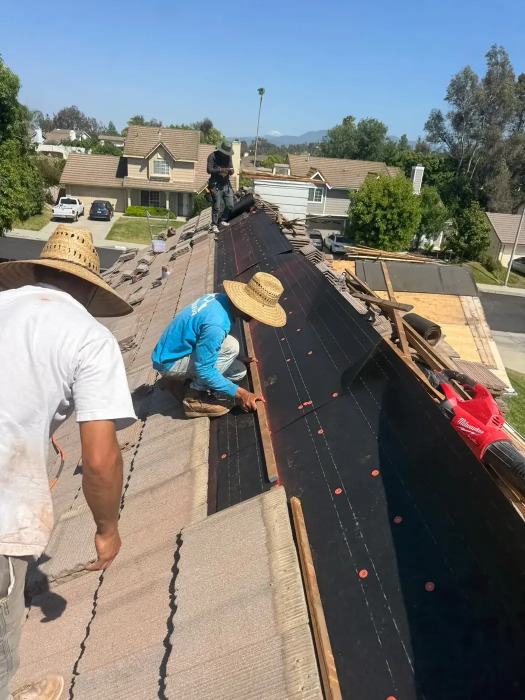 Roofer installing new underlayment on a tile roof
